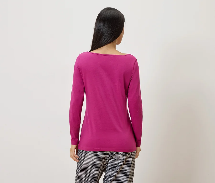 Rückansicht einer Frau mit langen, dunklen Haaren, die ein pinkes Langarmshirt und eine schwarz-weiß karierte Hose trägt.