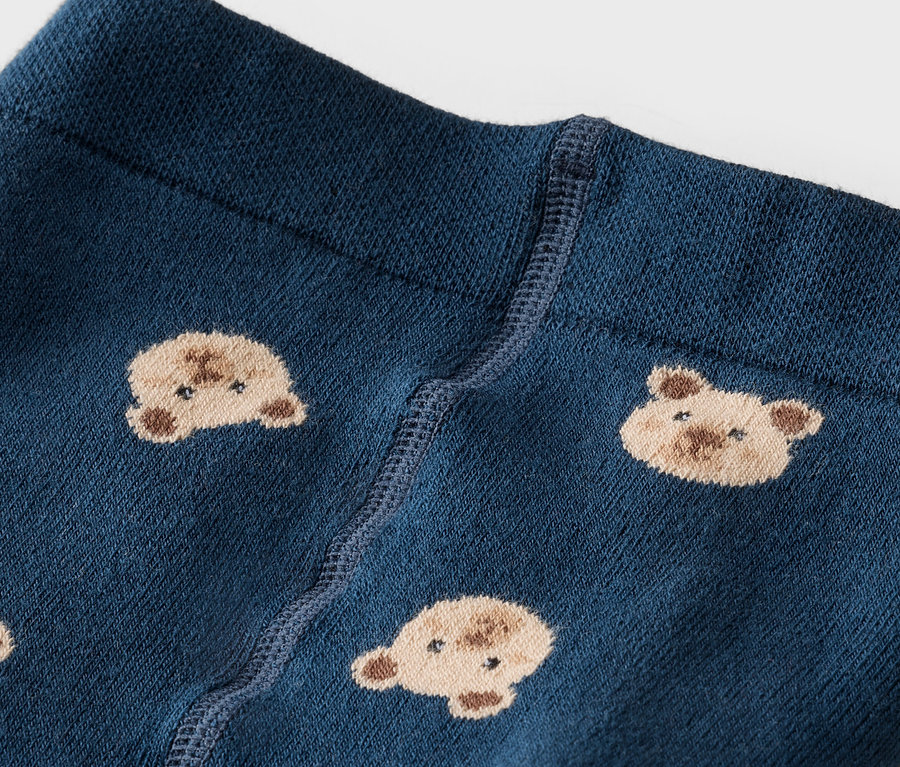 Nahaufnahme einer marineblauen Strumpfhose mit einem Bund und einem Muster aus Teddygesichtern.