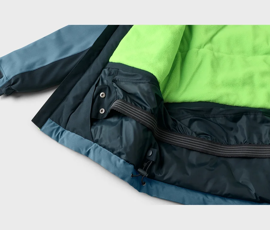Nahaufnahme einer blauen Jacke mit leuchtend neongrünem Fleecefutter, Schneefang mit Druckknöpfen und Kordelzug am Saum.