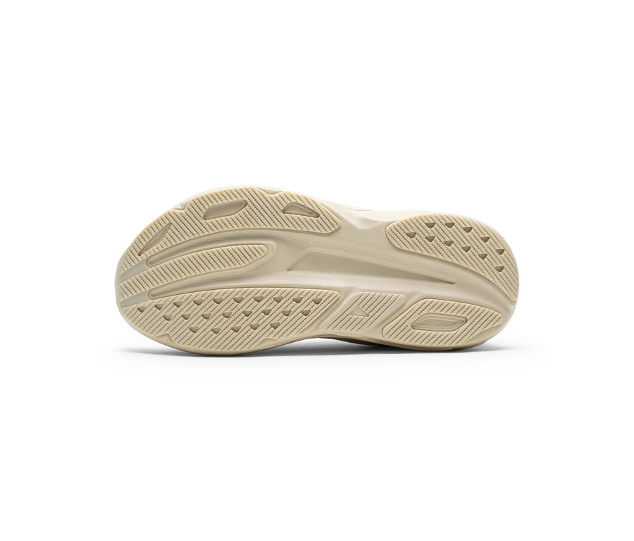 Beige Schuhsohle mit komplexem Profil aus Rillen und dreieckigen Noppen.