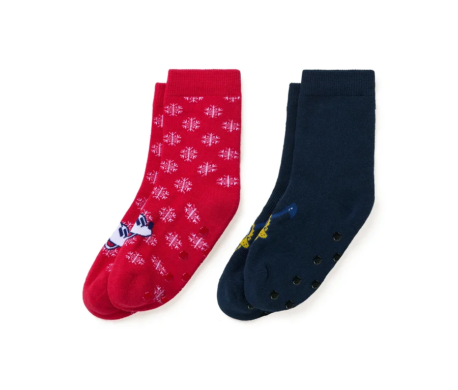 Zwei Paar Socken: rot mit weißen Schneeflocken und einer Zeichentrickfigur, und dunkelblau mit einer Zeichentrickfigur.