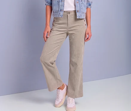 Eine Person trägt eine hellbeige Street One Cordhose mit Zierknöpfen, eine Jeansjacke und rosa-weiße Sneaker.