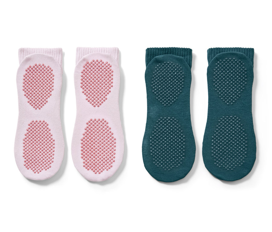 Zwei Paar Yogasocken. Ein Paar ist rosa mit rosa Noppen, das andere Paar ist grün mit grünen Noppen.