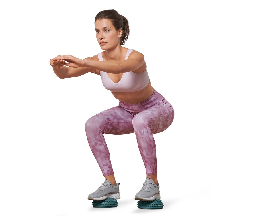 Eine Frau macht Kniebeugen auf 2 Balance-und-Massage-Pads.