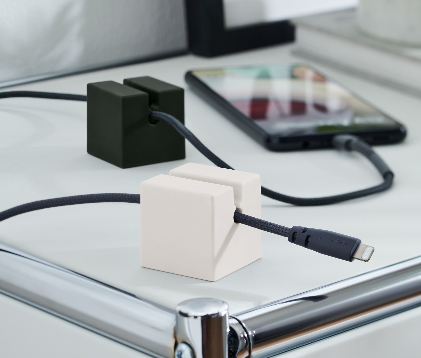 Ein Ladekabel-Organizer, 2er-Set, hält Ladekabel auf einem weißen Tisch. Einer ist schwarz und der andere weiß.