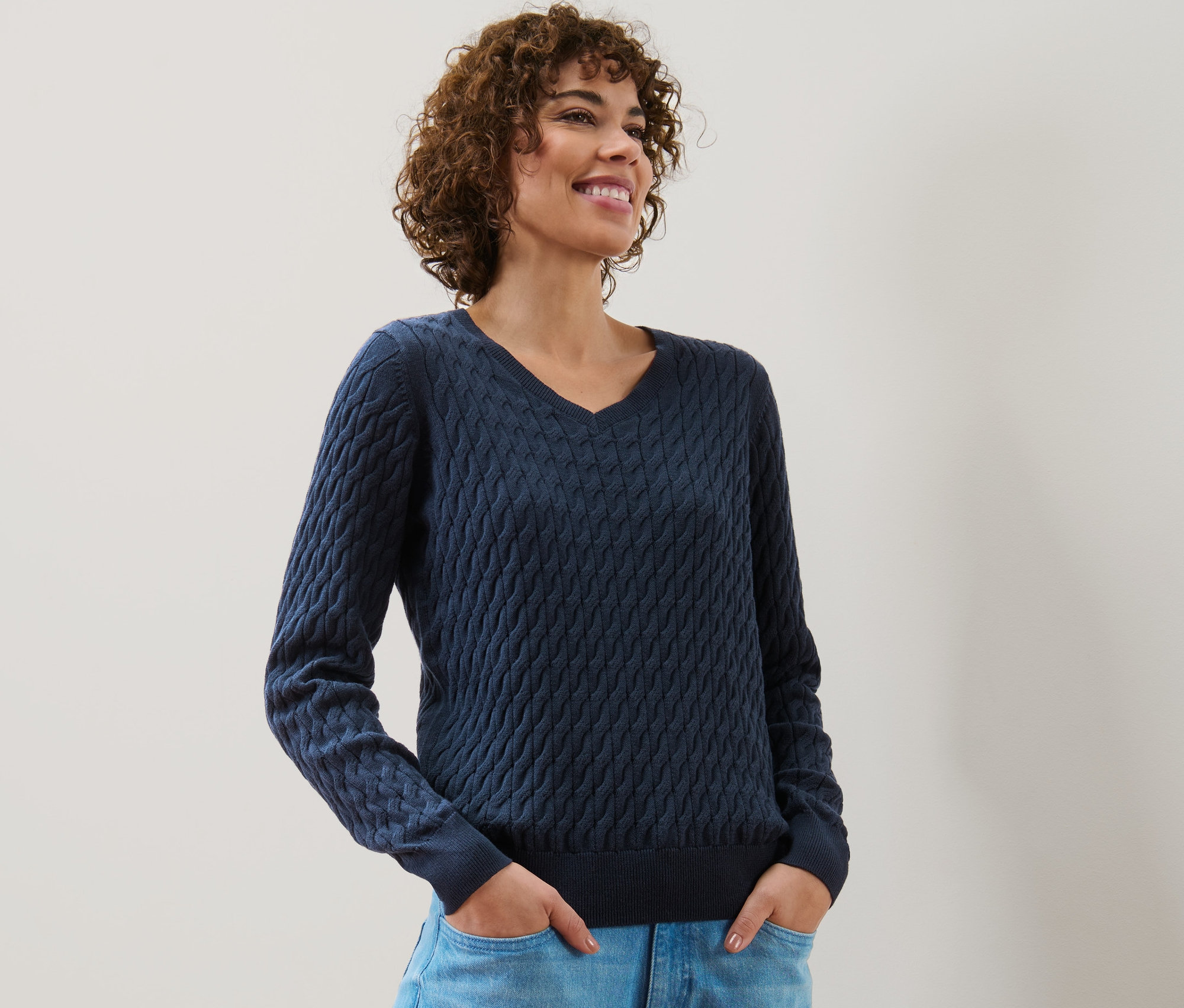 Frau trägt dunkelblauen Zopfstrickpullover.