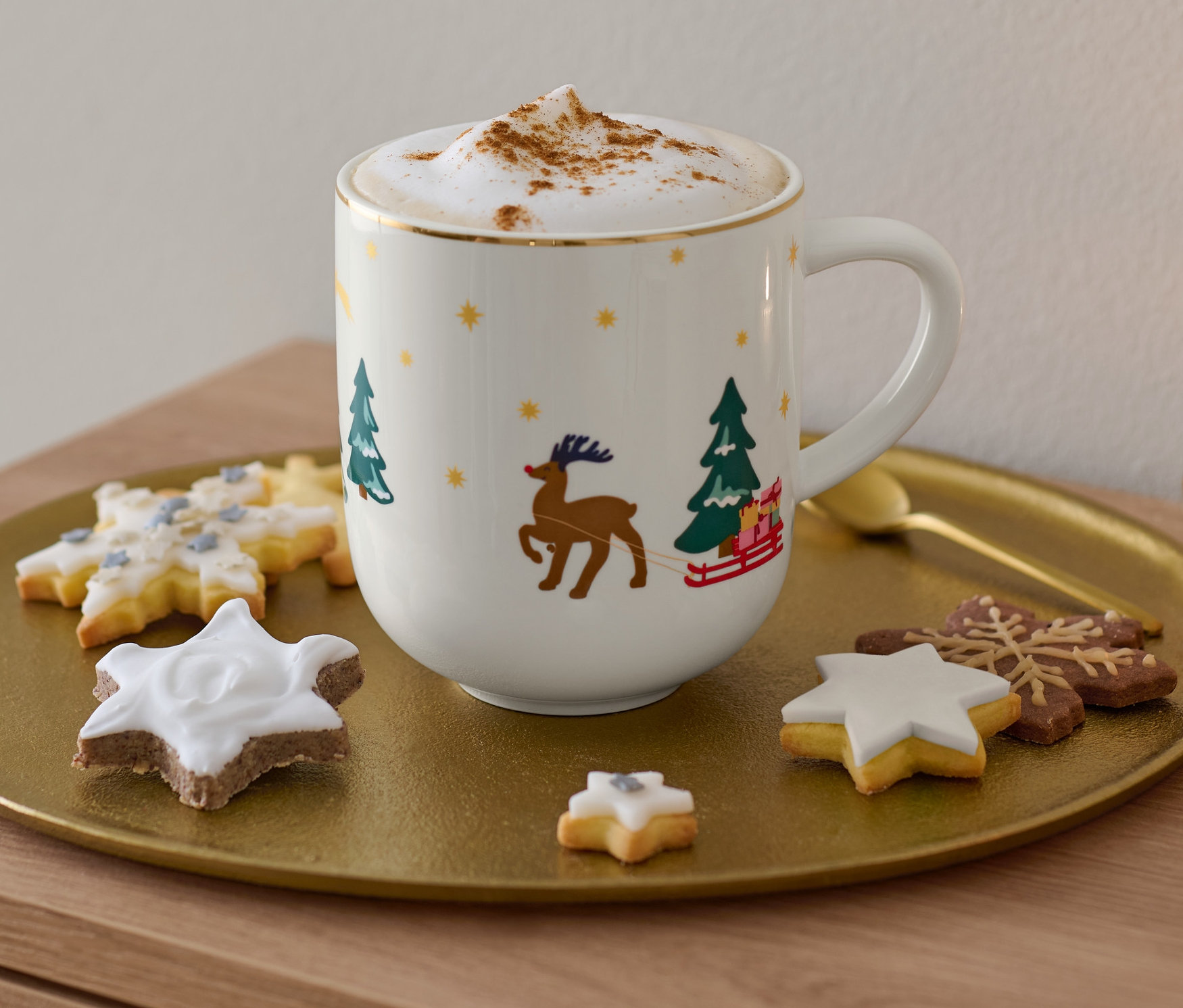 Auf einem goldenen Tablett stehen ein Jumbobecher mit Glanzgolddekor, ein Cappuccino und Kekse.