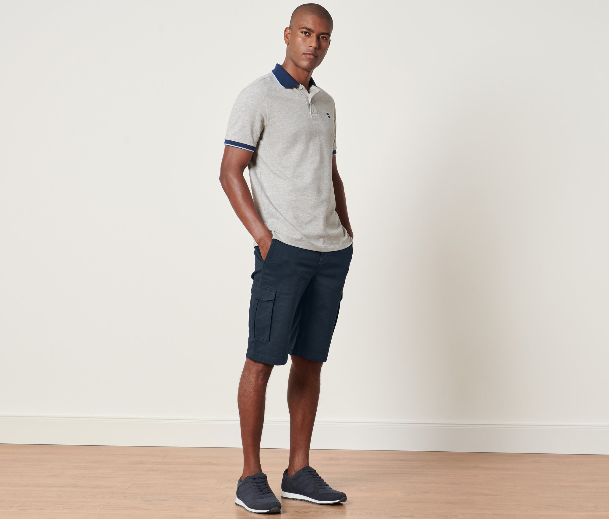 Mann steht mit Händen in den Taschen der navy Cargo-Shorts.