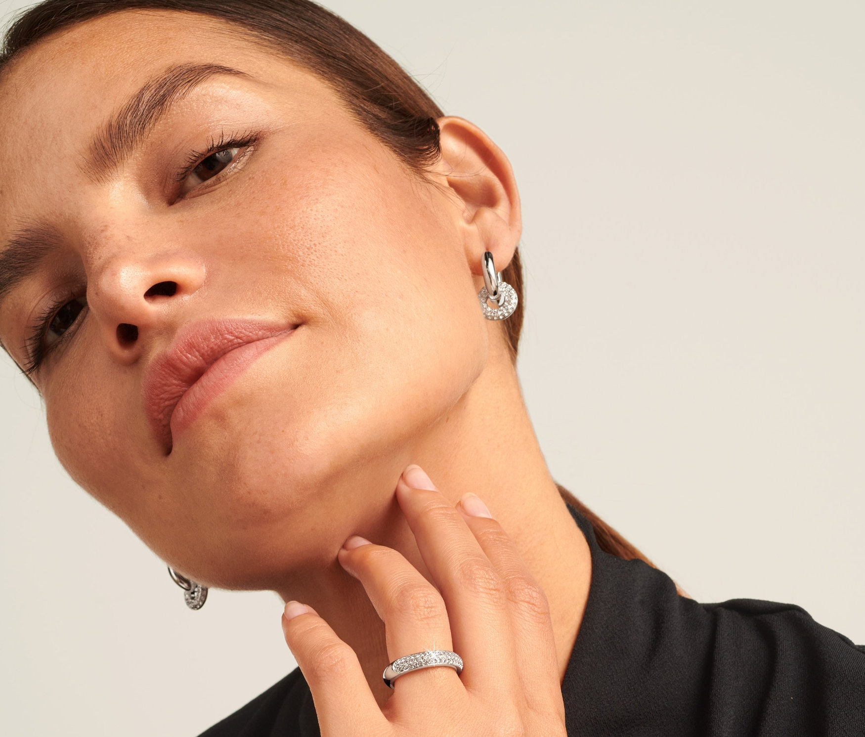 Frau mit silbernem Ring Sparkle Donut am Ringfinger und Ohrringen.