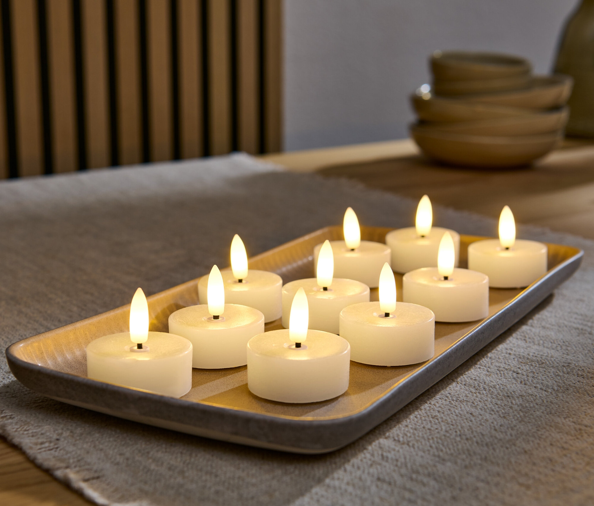 Zehn cremeweiße LED-Echtwachs-Teelichter liegen auf einem Tablett.