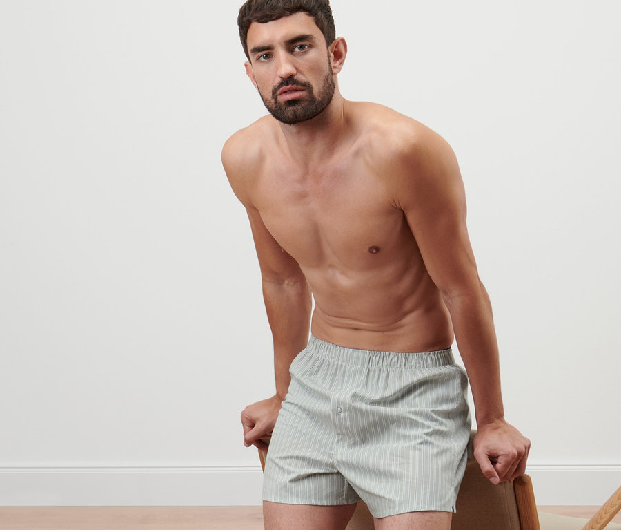 Mann, der sich an einen Stuhl lehnt, trägt 2 Web-Boxershorts.