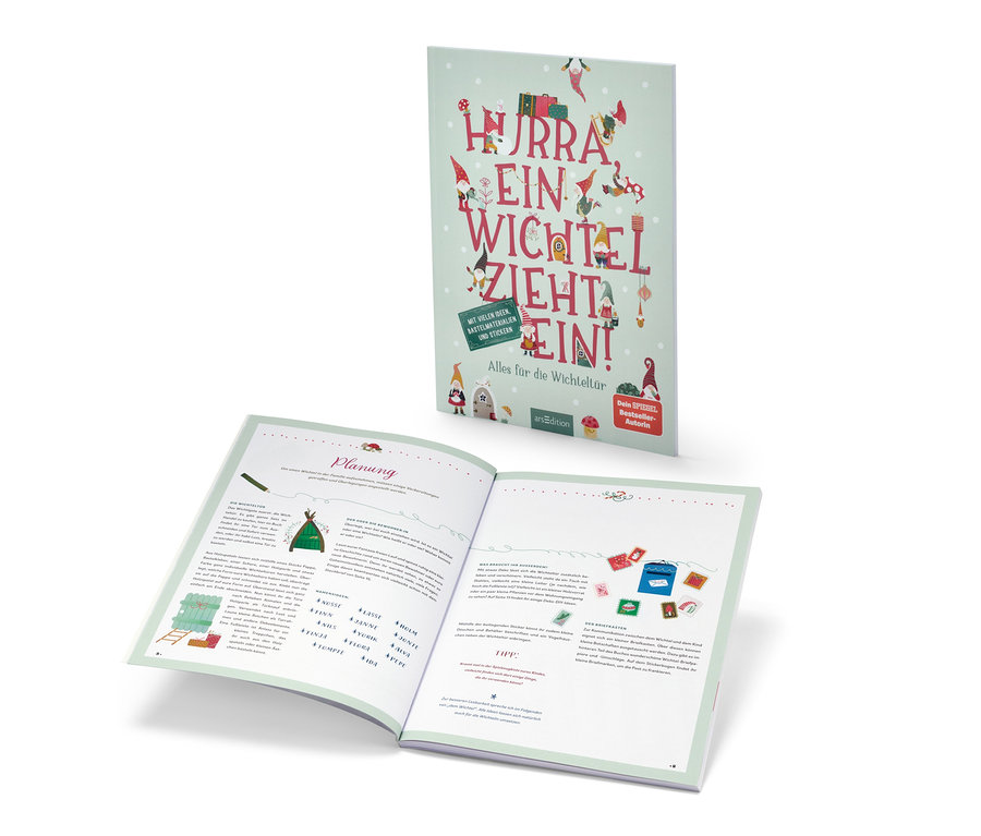 Das Buch »Hurra, ein Wichtel zieht ein!« ist geöffnet und steht dahinter.