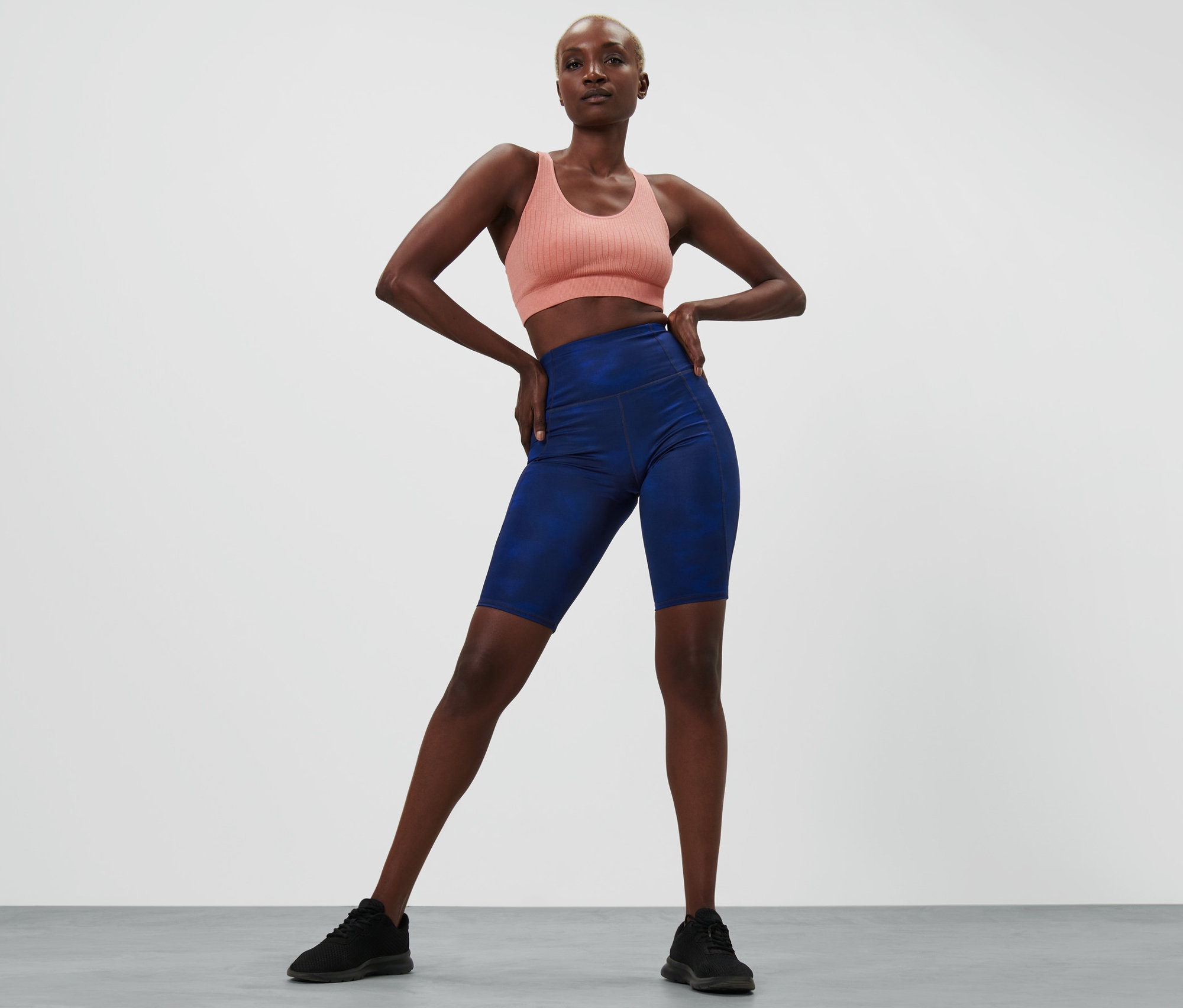 Frau posiert in Sport-BH und blauen Sportradler.