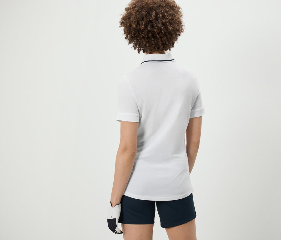 Rückansicht einer Frau mit lockigem Haar in einem weißen Funktionspoloshirt.