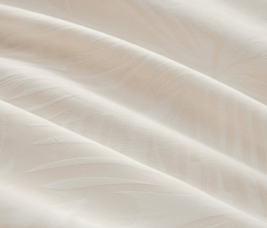 Detailaufnahme eines cremefarbenen Stoffes mit dezentem Muster und Faltenwurf.