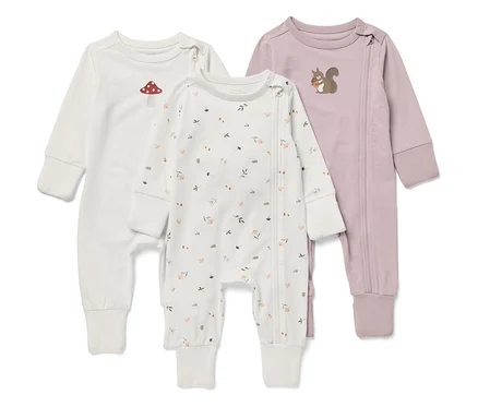 Drei langärmelige Baby-Overalls. Einer ist weiß mit einem Fliegenpilz, einer mit einem Blumenmuster und einer ist lila mit einem Eichhörnchen.