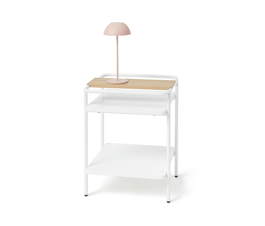 Weißer Beistelltisch mit heller Holzoberfläche und rosa Lampe.