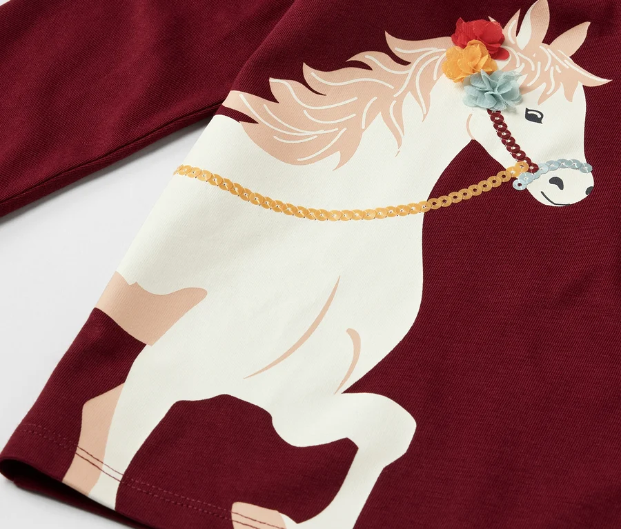 Detailaufnahme eines bordeauxroten Kinder-Langarmshirts mit Pferde-Aufdruck.