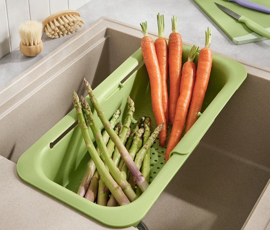 Karotten und Spargel liegen in einem grünen Abtropfbehälter im Spülbecken.