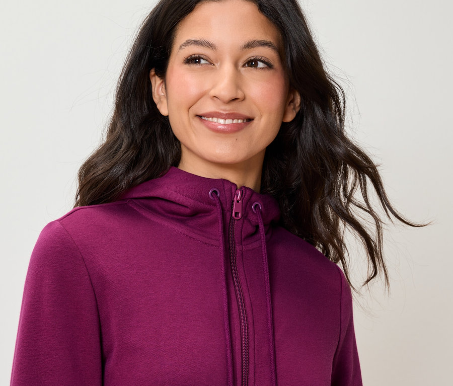 Lächelnde Frau trägt einen violetten Kapuzenpullover.