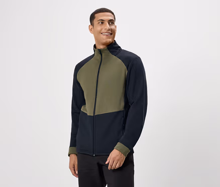 Mann lächelt und trägt eine olivgrüne und marineblaue Reißverschlussjacke.