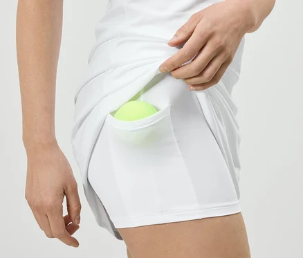 Frau legt Tennisball in die Tasche des weißen Sportkleids mit Radler.