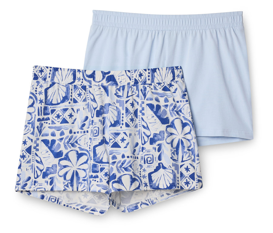 Zwei Shorts, eine hellblaue unifarbene und eine weiß-blaue gemusterte mit Muschel- und Blättermotiven, liegen übereinander.