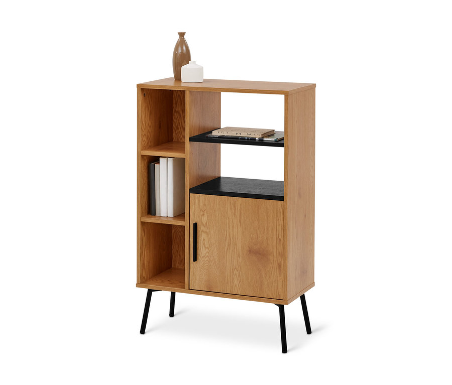 Ein hellbrauner Holzschrank mit schwarzen Akzenten und mehreren Fächern. Links drei offene Regalfächer, das mittlere enthält drei weiße Bücher. Rechts oben ein offenes Fach mit schwarzem Regalbrett und Papieren, darunter ein geschlossenes Fach mit Holztür und schwarzem Griff. Oben stehen eine hohe braune Vase und ein kleines weißes Dekoobjekt. Der Schrank steht auf vier schwarzen Metallbeinen.