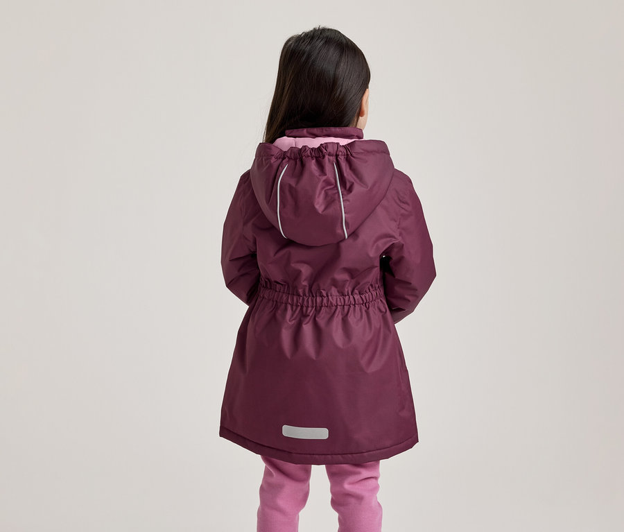Kind von hinten in einer pflaumenfarbenen Jacke mit Kapuze, reflektierenden Streifen und rosa Hose.