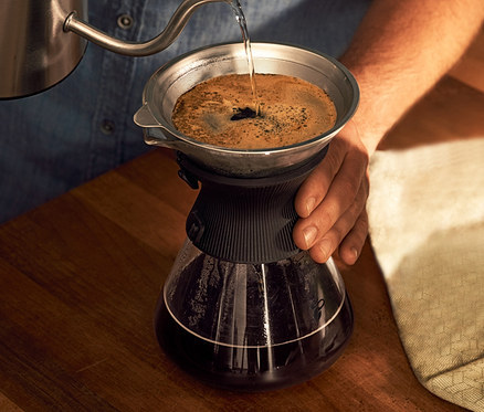 Mann gießt Wasser in eine BEEM Pour Over, 0,75 l Glaskaraffe mit Kaffeefilter.