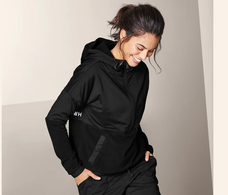 Frau trägt einen schwarzen Hybrid-Fleecesweater und eine schwarze Hose.