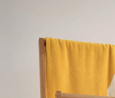 Ein gelb-weiß gestreiftes Jacquard-Badetuch und zwei beige-weiß gestreifte Handtücher hängen auf einem Klappbaren Kleiderständer. Darunter stehen 2 Aufbewahrungskörbe.