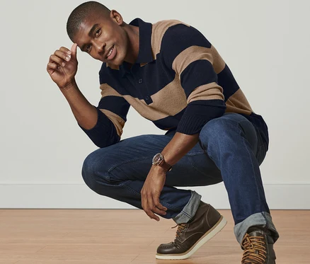 Mann in gestreiftem Pullover mit Cashmere-Anteil posiert hockend.