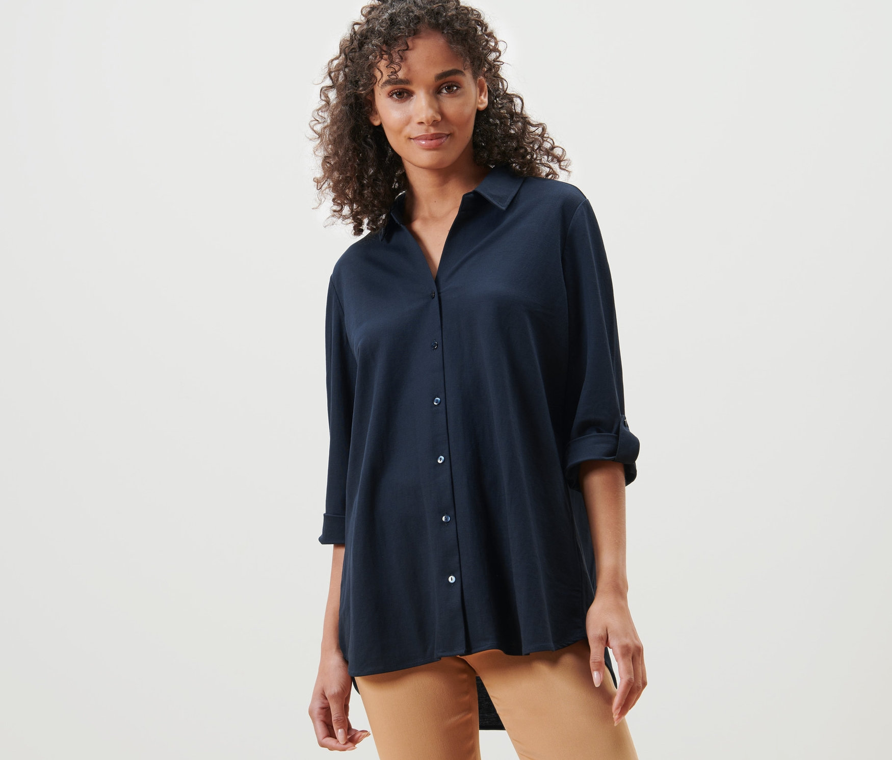 Frau posiert in dunkelblauer Piqué-Jerseybluse und brauner Hose.