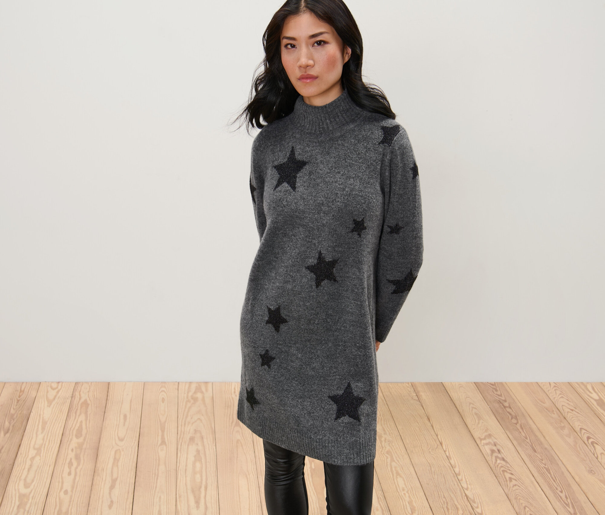 Frau posiert in einem Strickkleid mit Rollkragen.