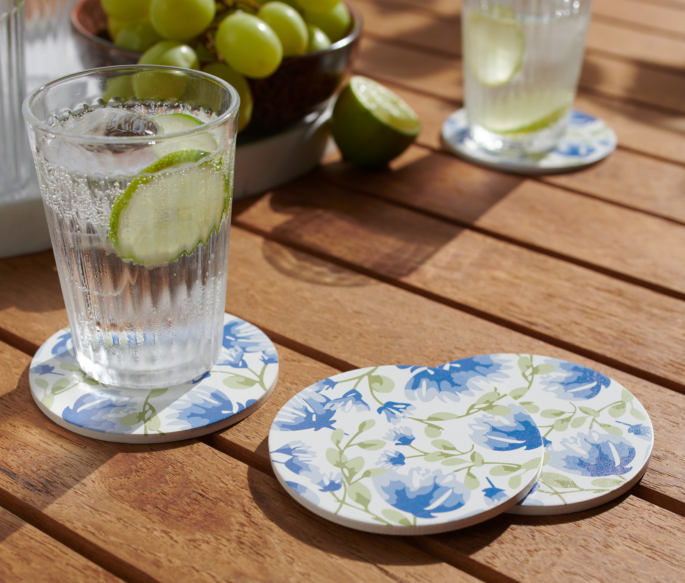 Ein Glas mit Getränk steht auf einem der 4 Getränkeuntersetzer auf einem Holztisch.