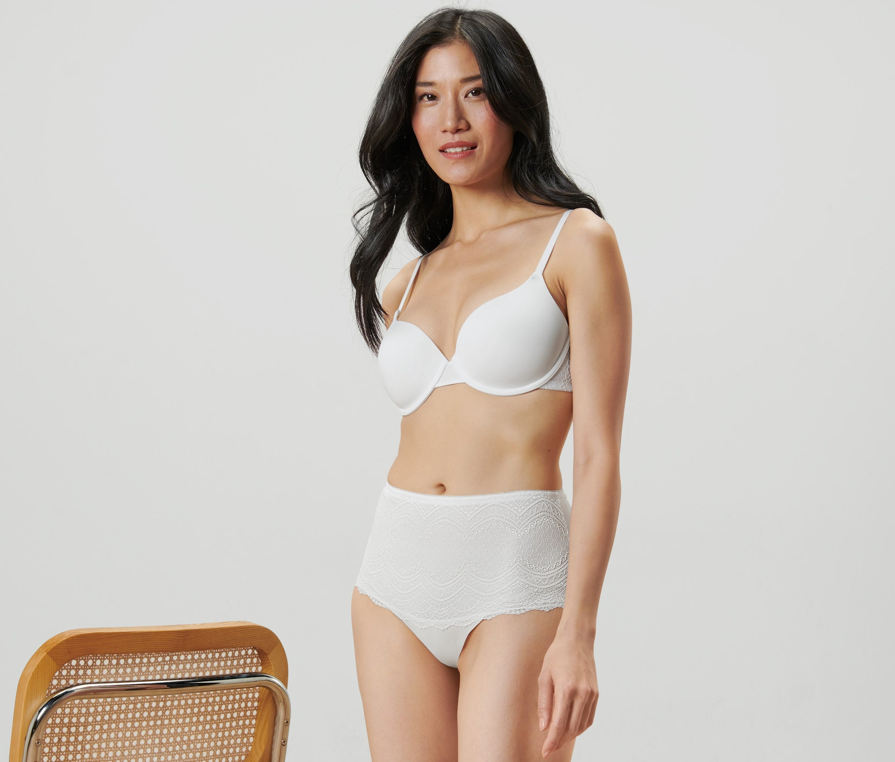Frau posiert in weißem BH und Highwaist-Panty.