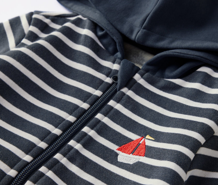 Gestreifte Kinder-Sweatjacke mit Kapuze und angerauter Innenseite mit kleinem Segelboot-Motiv.
