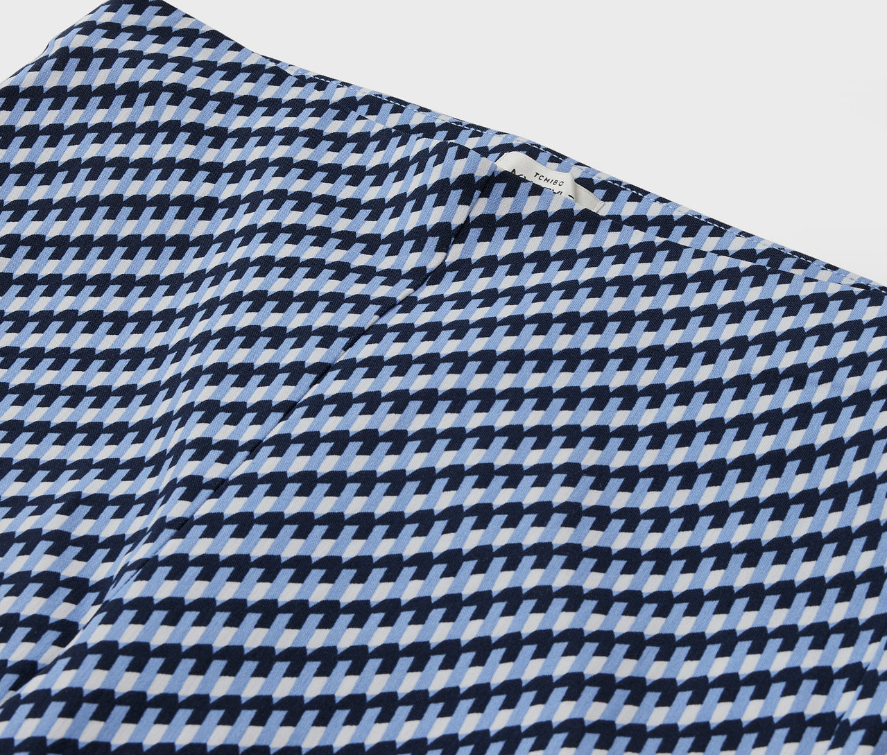Detailaufnahme eines gemusterten Stoffes mit geometrischem Design in Blau und Weiß.
