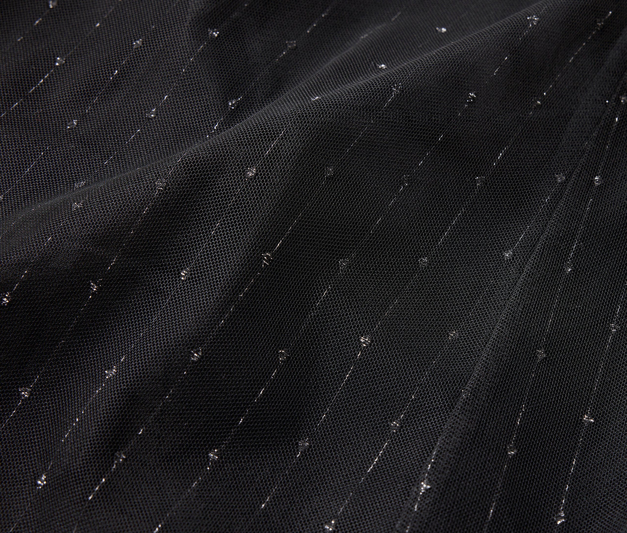 Detailaufnahme eines schwarzen Stoffes mit diagonalen silbernen Streifen und Punkten.
