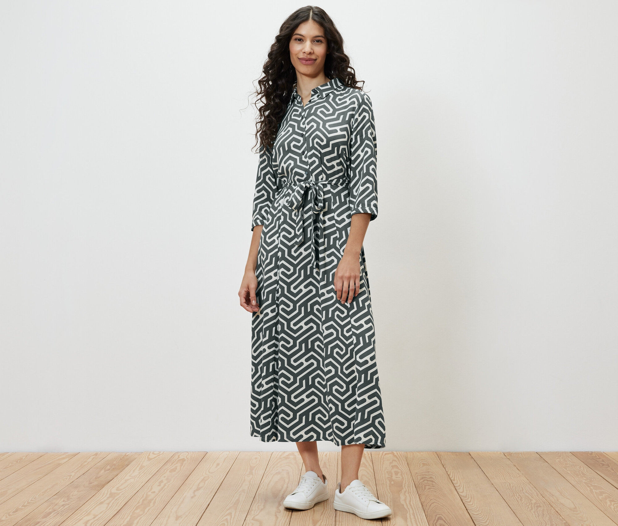 Frau steht und trägt ein bedrucktes Hemdblusenkleid.