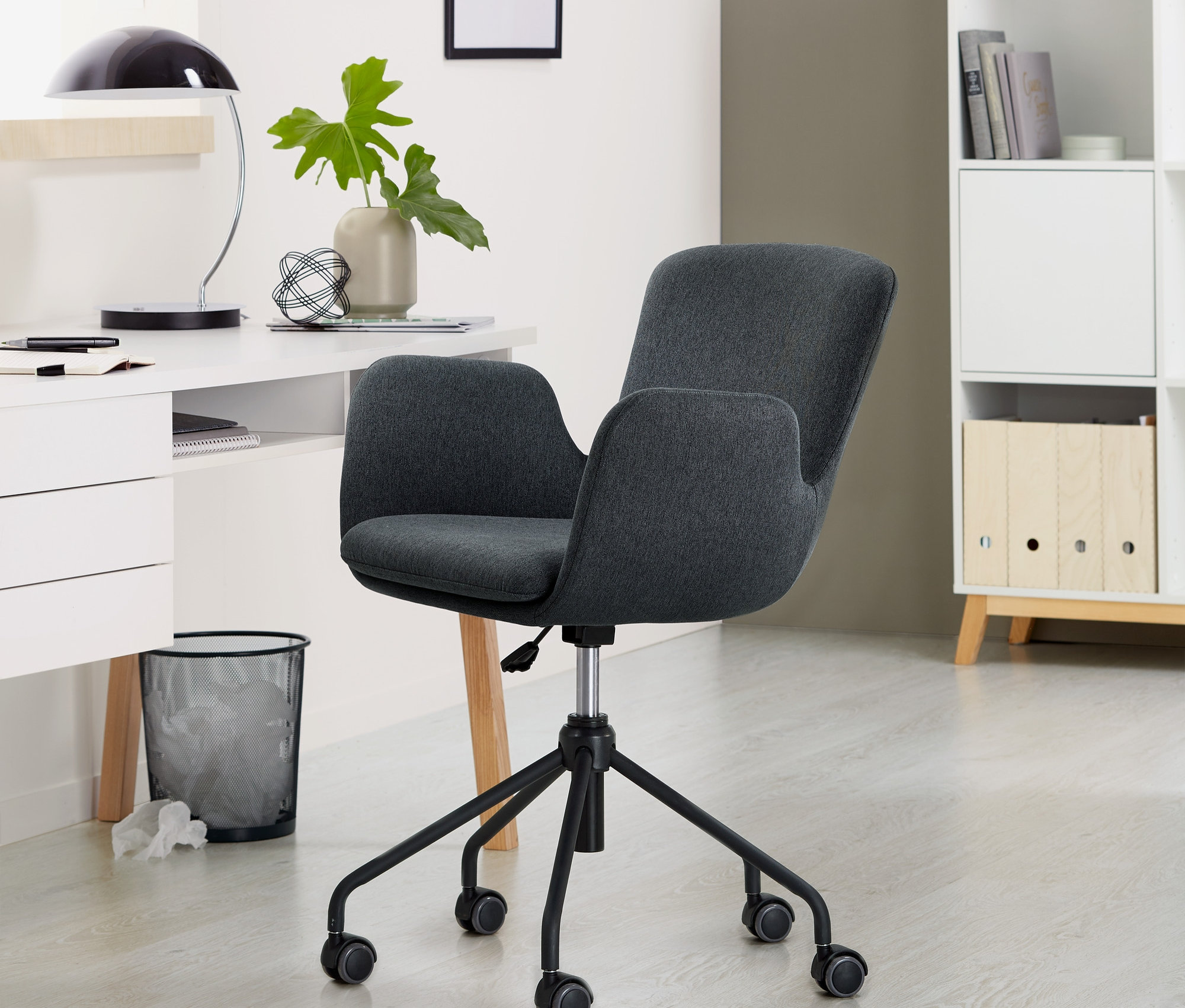 Ein anthrazitfarbener Schreibtischstuhl steht im Raum.