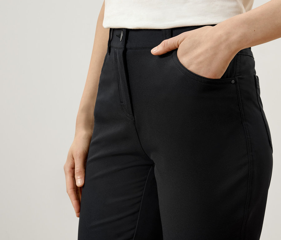 Frau hat Hand in der Tasche einer schwarzen Hose.