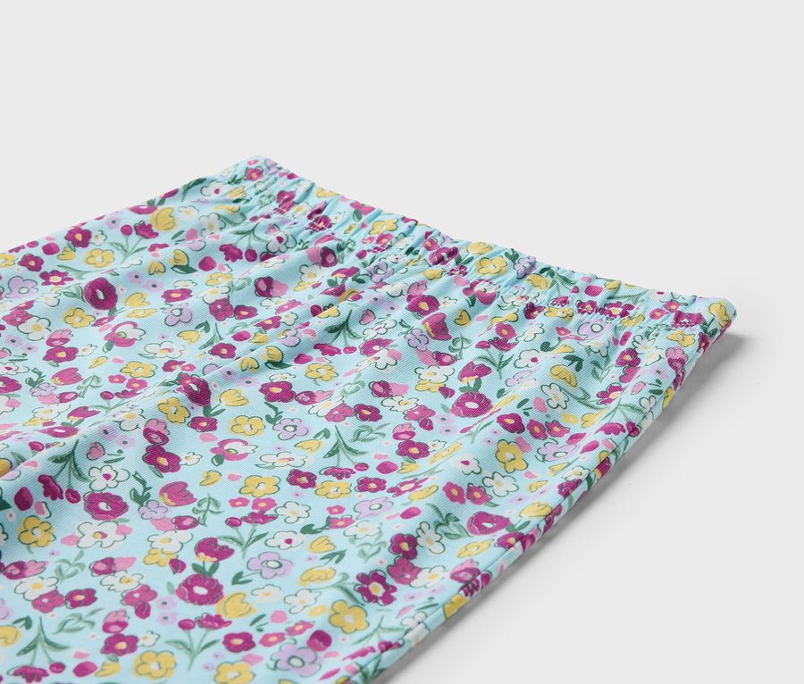Detail einer hellblauen Hose mit Blumenmuster und Gummibund.