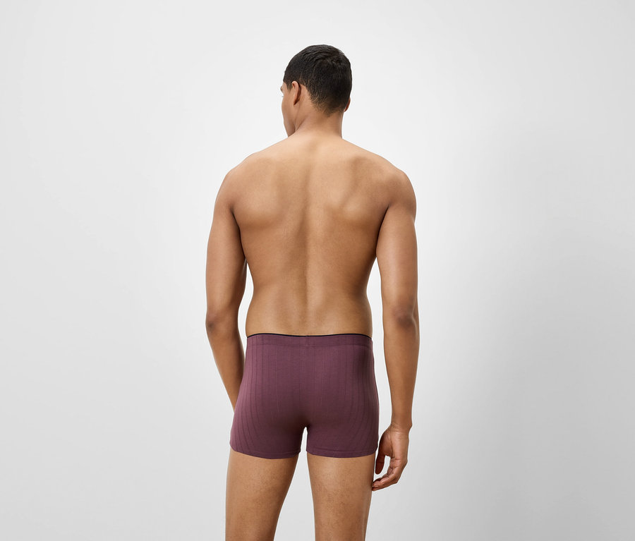 Mann von hinten trägt violette Boxershorts.