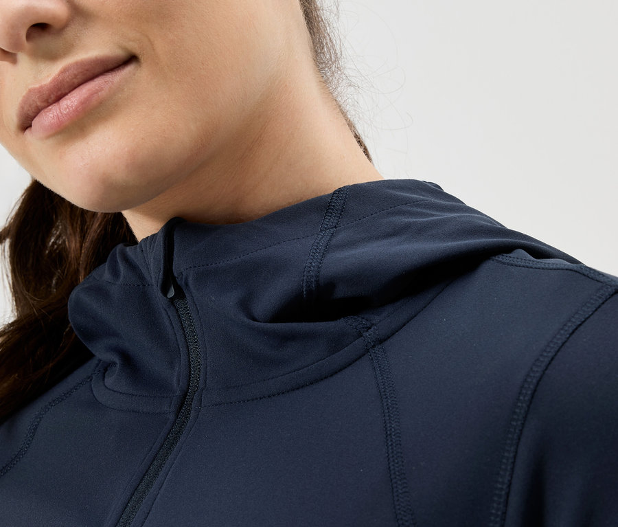 Nahaufnahme einer Frau mit Kapuze und Reißverschlussjacke in Marineblau.