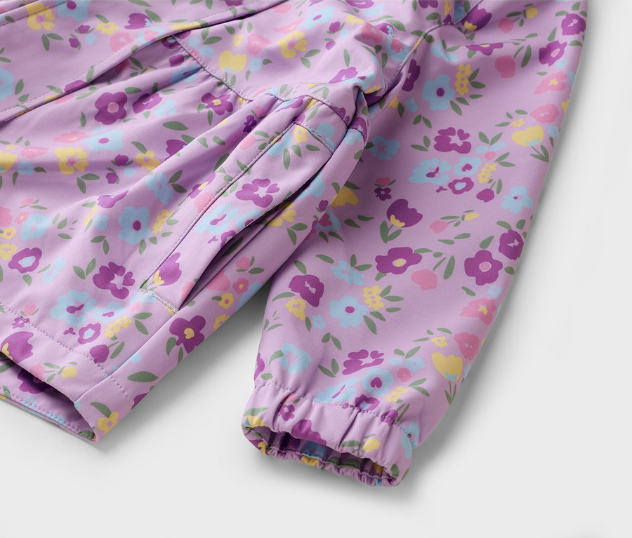 Nahaufnahme einer lila Jacke mit Blumenmuster, die auf einer weißen Oberfläche liegt.