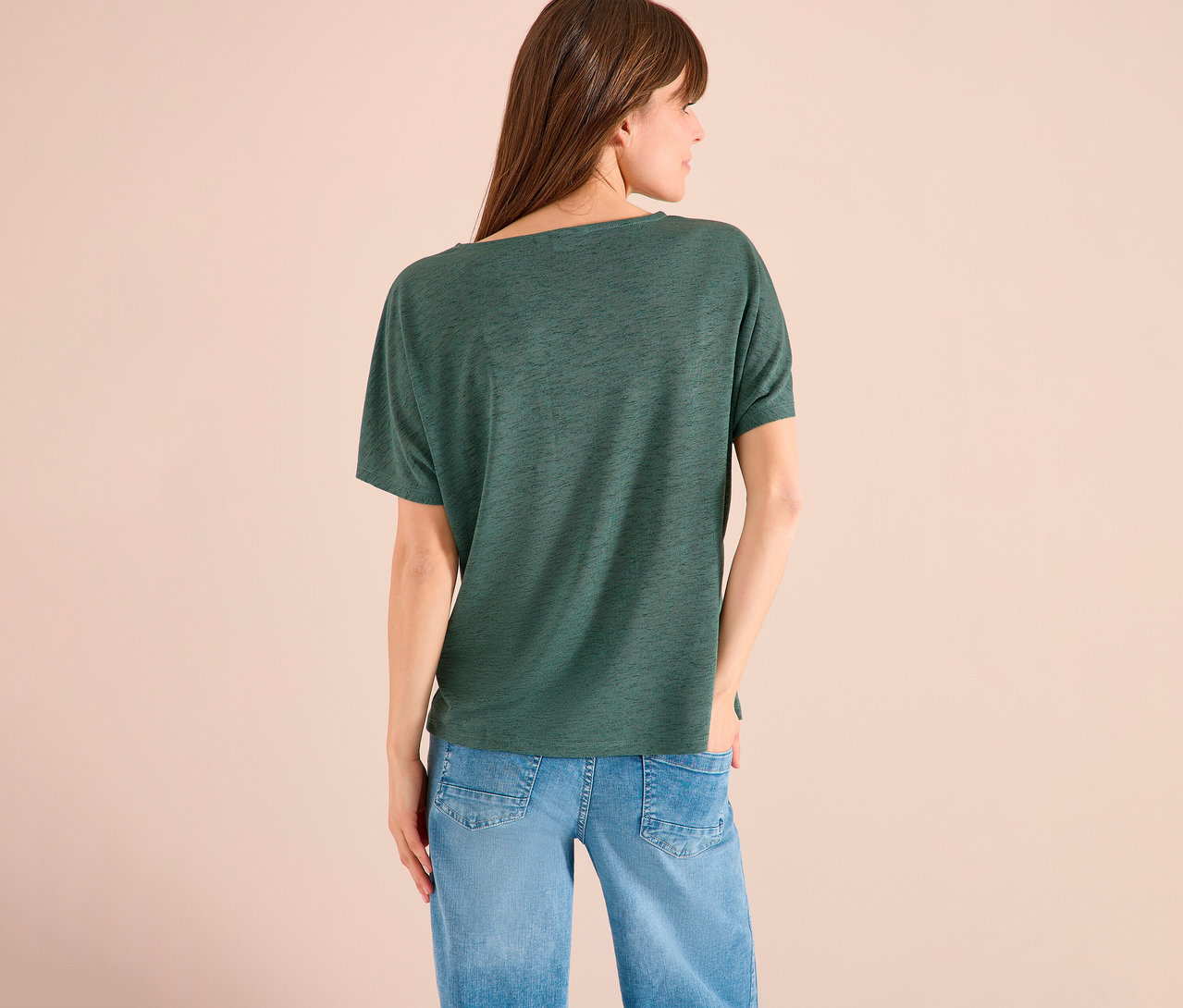 Rückansicht einer Frau mit braunen Haaren in einem grünen T-Shirt und blauen Jeans.