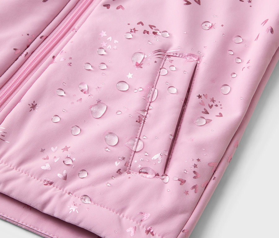 Nahaufnahme einer wasserabweisenden, hellrosa Jacke mit Reißverschluss und Tasche, die mit Herzen und Sternen bedruckt ist.