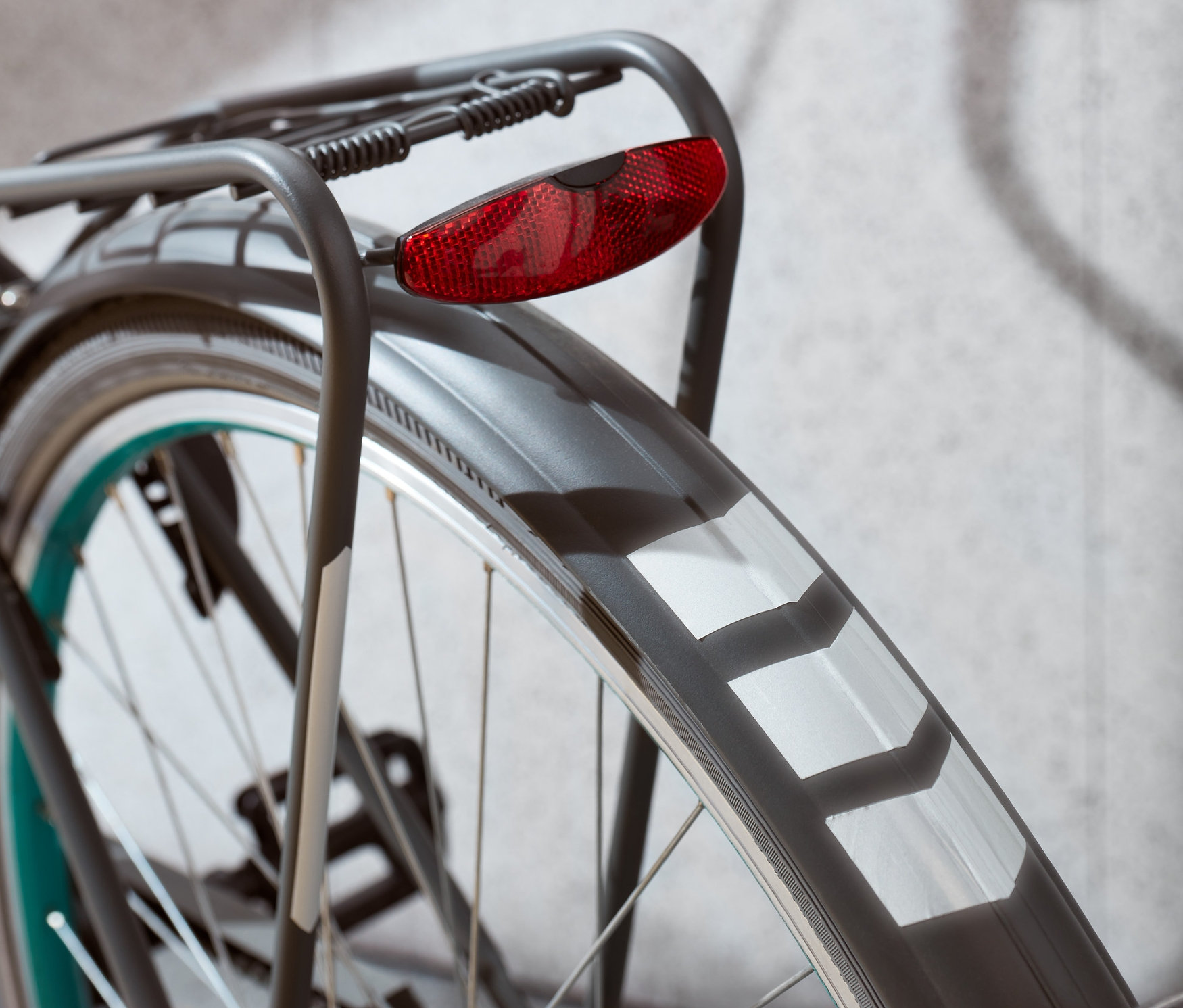 Detailaufnahme vom Hinterrad eines Fahrrads mit rotem Licht und reflektierenden Aufklebern.